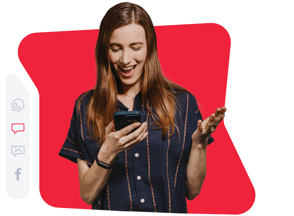 Woman in a navy shirt smiling while looking at her phone with a red background.