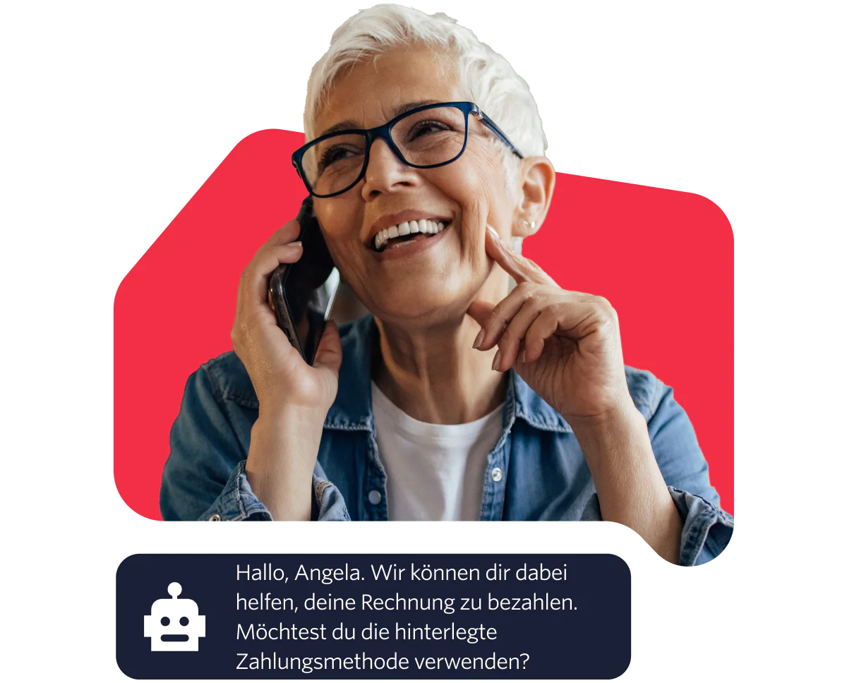 Elderly woman with glasses smiling while talking on the phone against a red background.