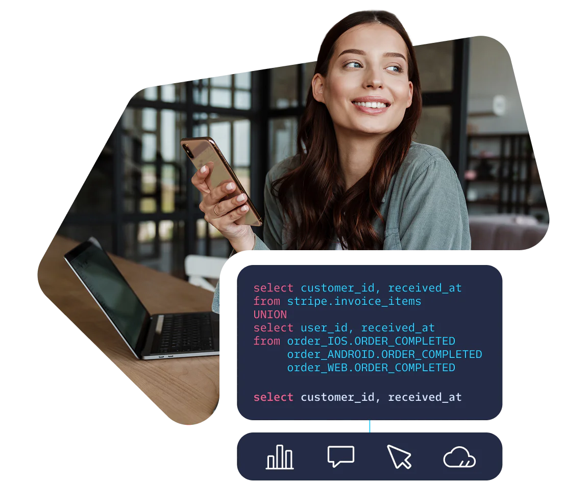 Smiling woman holding phone, sitting by a laptop with SQL code displayed on the screen.