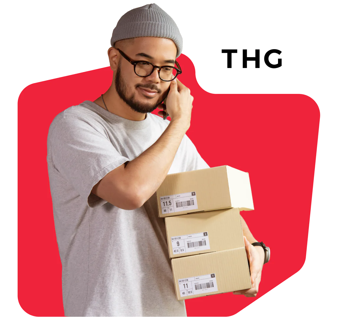 Man in gray beanie and glasses holding packages while on the phone