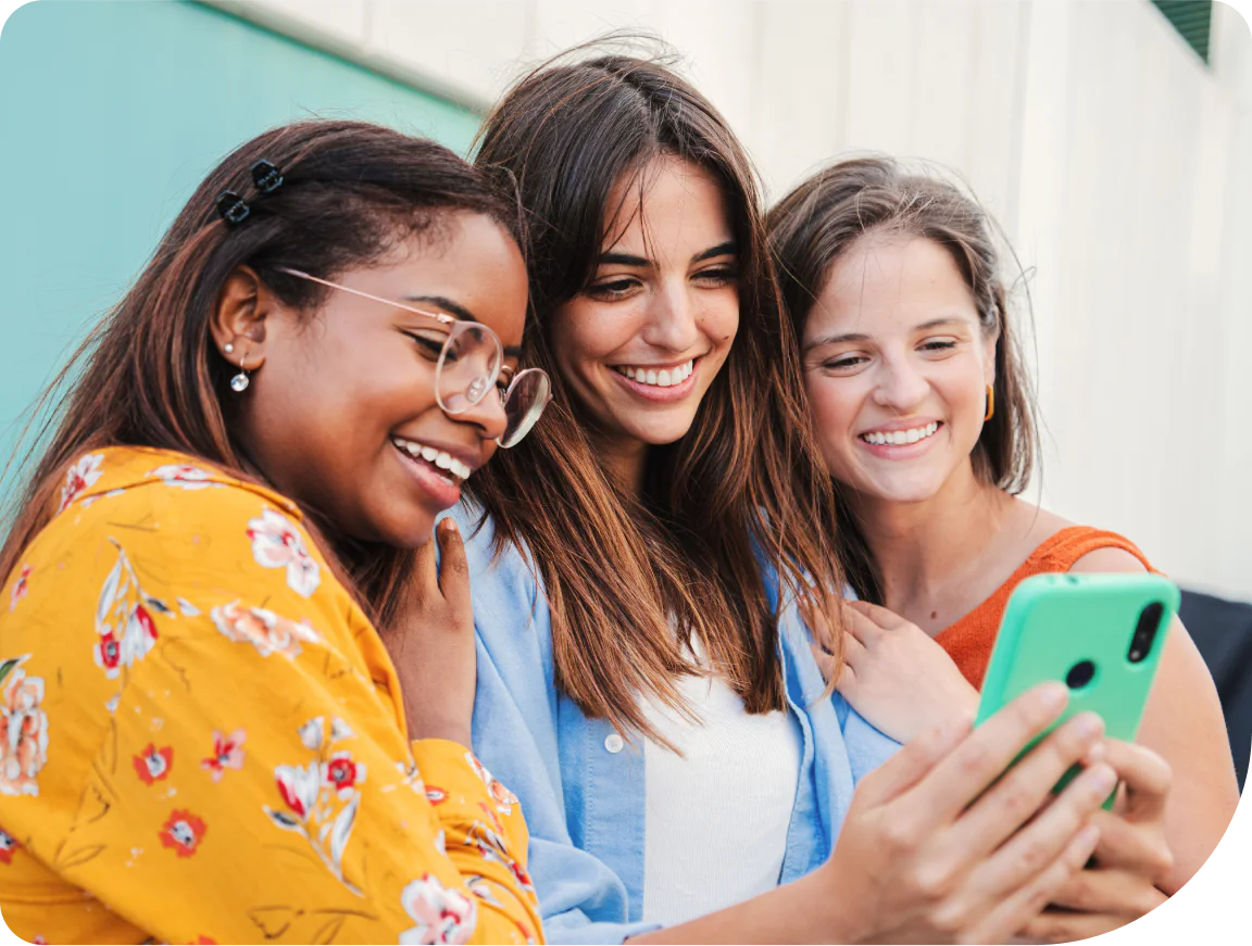 Three young women smiling and taking a selfie with a smartphone.