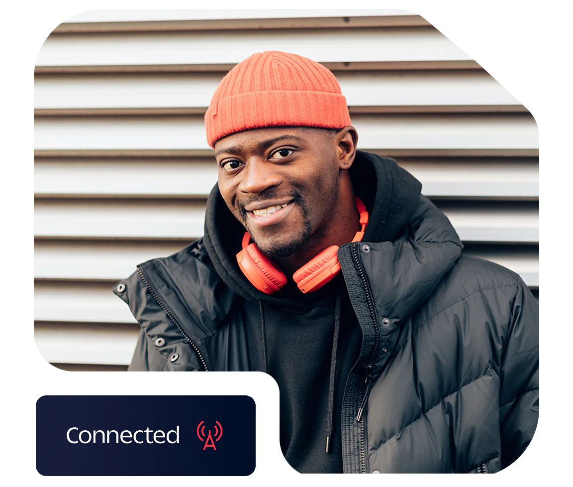 Man in red beanie and orange headphones smiling in front of striped wall