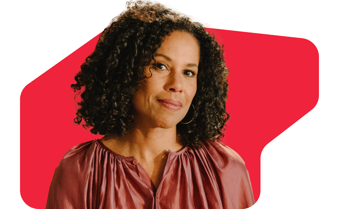 Woman with curly hair wearing a pink blouse against a red geometric background