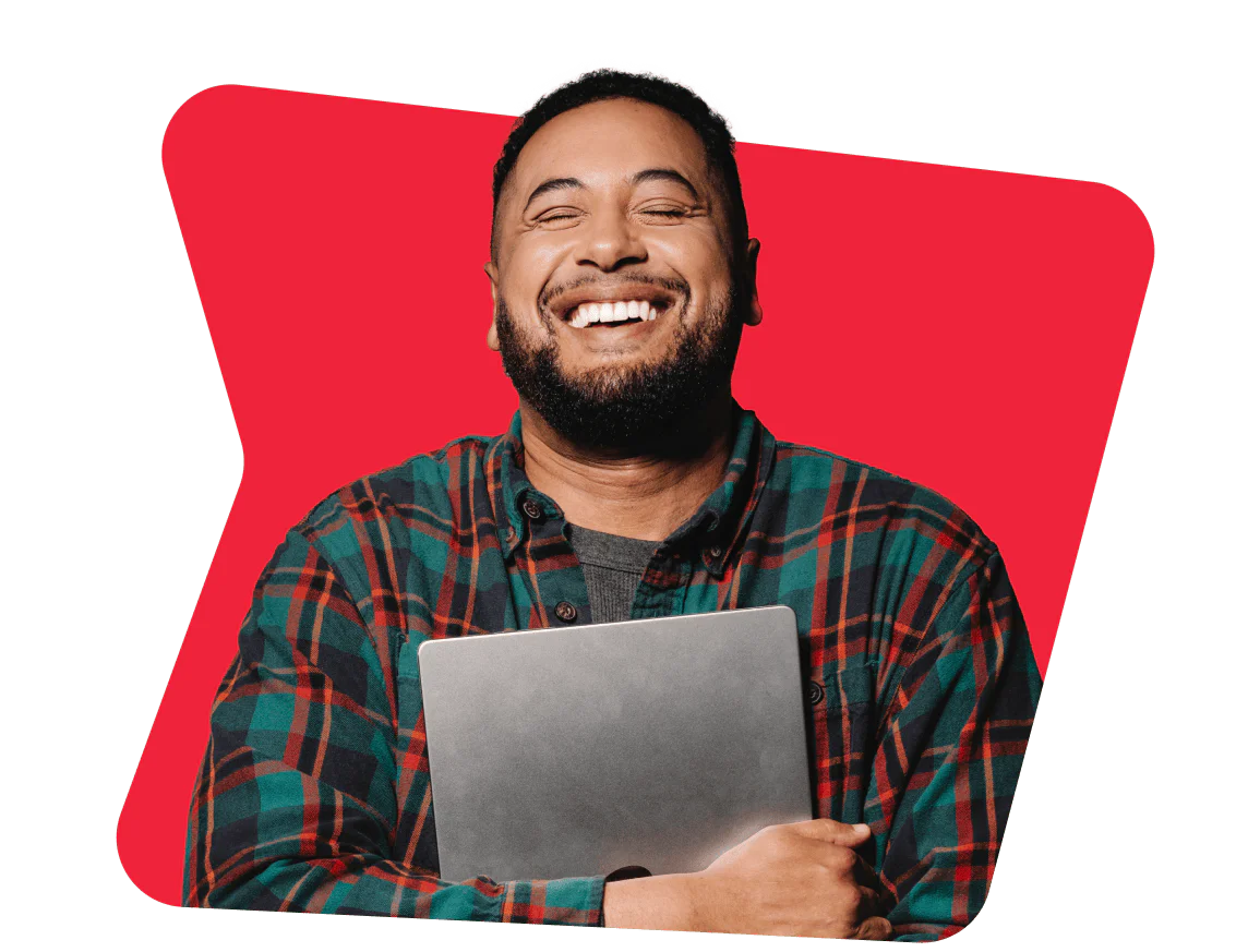 Man in a checkered shirt happily holding a laptop with a red background