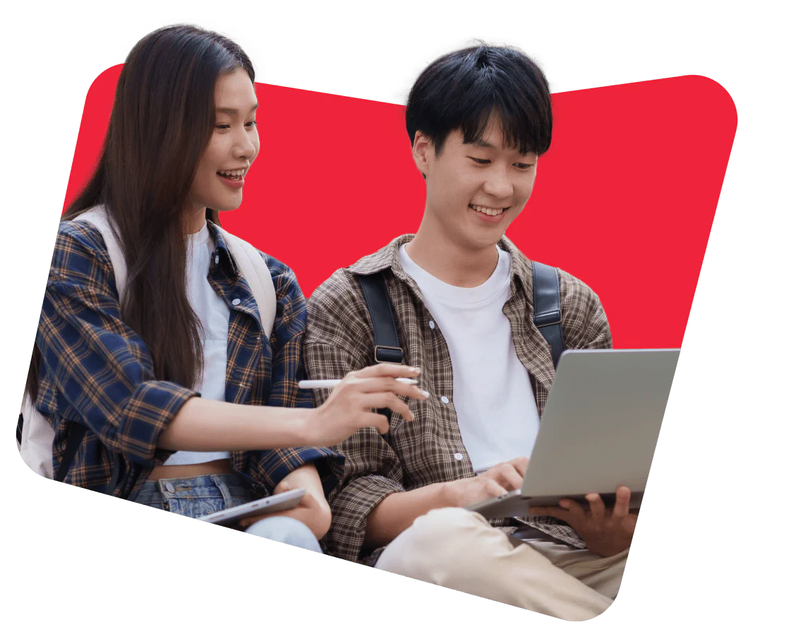 Two students with backpacks, one using a laptop while the other points at the screen.