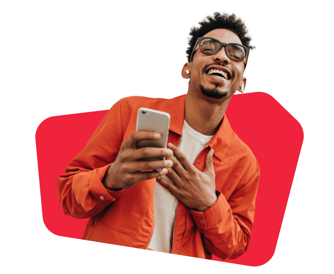 Man wearing glasses and orange jacket smiling while holding a smartphone