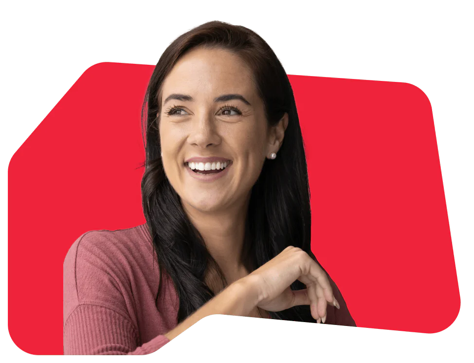 Woman with dark hair smiling and wearing a pink top in front of a red background